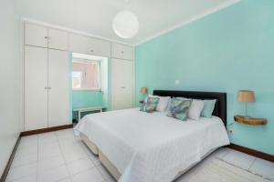 um quarto com uma cama branca e paredes azuis em Vilarosa Oceanside by Encantos do Algarve - 1B em Portimão