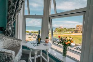 um quarto com uma mesa e uma janela com vista para o oceano em OYO Minerva Guesthouse em Newquay