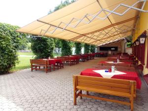 a restaurant with tables and benches and a large umbrella at Gut Drasing in Krumpendorf am Wörthersee