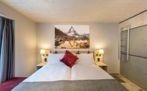 1 dormitorio con 1 cama con sábanas blancas y almohadas rojas en Hotel Derby, en Zermatt