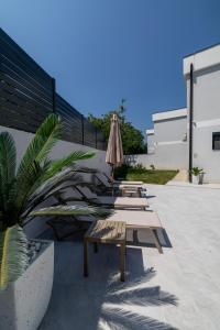 une terrasse avec des bancs, un parasol et une plante dans l'établissement Mi Casa, à Vrdnik