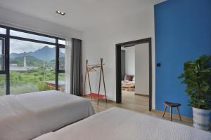 a bedroom with two beds and a large window at Heaven's Gate Home Stay in Zhangjiajie