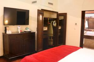 a bedroom with a bed and a television and a closet at Camino Real Antigua in Antigua Guatemala