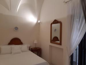 um quarto branco com uma cama e um espelho em Estlevante B&B em Vieste