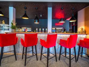 een bar met rode stoelen voor een balie bij JUFA Hotel Salzburg in Salzburg