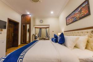 a bedroom with a large bed with blue and white pillows at Khattak Lodge Murree in Murree