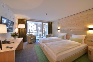 a hotel room with a large bed and a desk at Alpenhotel Fleurs de Zermatt in Zermatt