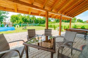 une terrasse avec une table et des chaises en verre ainsi qu'une aire de jeux dans l'établissement Mazurskie El Dorado, à Mikołajki