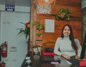 une femme assise sur un bureau avec un ordinateur portable dans l'établissement Rupa Rupa High Jungle Eco B&B, à Machu Picchu