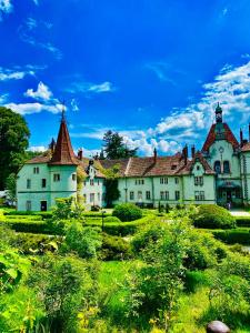 ein großes weißes Haus mit einem grünen Feld davor in der Unterkunft Кайзервальд Карпати in Karpaty