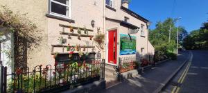 a building with a red door and flowers on a street at Holly Cottages in Bowness-on-Windermere