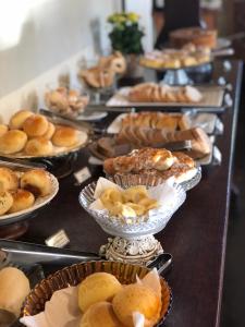 ein Buffet mit Kuchen und Gebäck in Schalen in der Unterkunft Pousada Casagrande in Pirenópolis