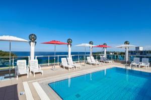 ein Pool mit Stühlen und Sonnenschirmen auf einem Gebäude in der Unterkunft Hotel Gran Vista Plava Laguna in Poreč