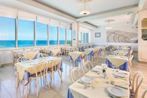 ein Restaurant mit Tischen und Stühlen mit Meerblick im Hintergrund in der Unterkunft Hotel Gran Vista Plava Laguna in Poreč