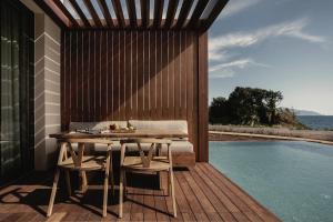 a wooden deck with a table and chairs next to a swimming pool at Meraviglia Slow Living in Preveza