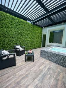 eine Terrasse mit Whirlpool-Badewanne und grüner Wand in der Unterkunft Fato Hotel in Querétaro