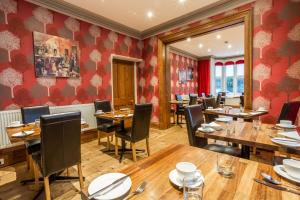 a restaurant with wooden tables and chairs and red walls at Jerichos Boutique Accommodation in Windermere