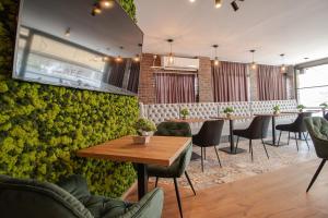 een restaurant met een groene muur met tafels en stoelen bij OASIS Apartments in Gevgelija