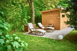 een houten terras met twee stoelen en een tafel en een gebouw bij Landhaus Dodo in Payerbach