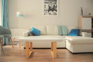 a living room with a white couch and blue pillows at Apartamento Dulcinea in Alcalá de Henares