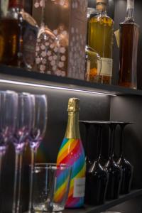 - une bouteille de vin assise sur une étagère à côté des verres dans l'établissement Elite Hotel - Gay Men Only, à Sitges