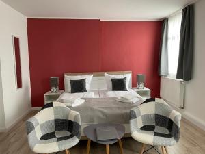 um quarto vermelho com uma cama e 2 cadeiras em Pension Altstadt em Veimar