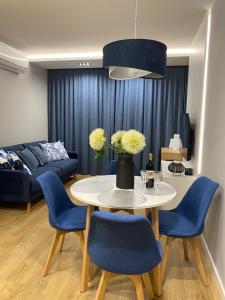 ein Wohnzimmer mit einem Tisch und blauen Stühlen in der Unterkunft Family & Business Elegant Apartments Wspólna Centrum Downtown - 1 Bedroom, Terrace, Air Conditioning, Garage, NEW! in Kielce