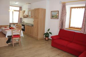 a living room with a red couch and a table at Appartamenti Dany in Arabba