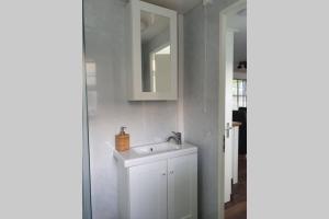 La salle de bains est pourvue d'un lavabo blanc et d'un miroir. dans l'établissement Vazonics Valkenbosch 76, à Oisterwijk