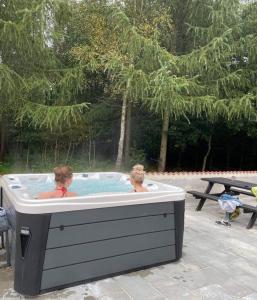 twee personen in een hot tub met een picknicktafel bij Emda Country living close to Legoland in Billund