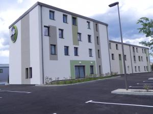 un gran edificio blanco con aparcamiento en B&B HOTEL Aubenas, en Saint-Didier-sous-Aubenas