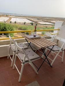 - une table et des chaises sur un balcon avec une bouteille de vin dans l'établissement Apartamento Aldeia de Marim, Ohao, Portugal, Meerblick, à Olhão