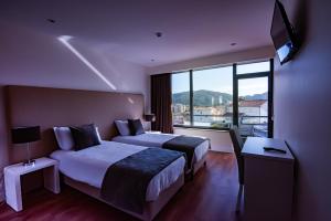 a hotel room with two beds and a large window at Hotel Quinta do Viso in Miranda do Corvo