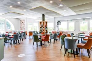 un comedor con mesas, sillas y ventanas en Hôtel Jules Verne Biarritz, en Biarritz