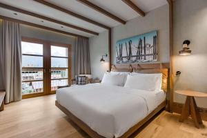 Un dormitorio con una gran cama blanca y una ventana en Grand Hotel Savoia Cortina d'Ampezzo, A Radisson Collection Hotel, en Cortina dʼAmpezzo