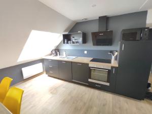 瑟堡Appartement 5 Cherbourg centre avec NETFLIX et WIFI的一间厨房,里面配有黑色家电和黄色椅子