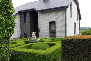 a garden in front of a house with a statue at Bonheur à la campagne in Bastogne