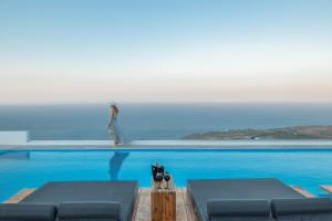 a woman is standing on the edge of a swimming pool at Oyster Luxury Suites in Imerovigli