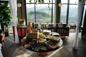 un buffet de comida en una mesa en una habitación con ventanas en Mountain Residence Apartments & Chalet, en Bukovel