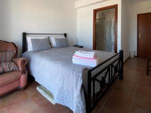 a bedroom with a bed with a black frame and a chair at Vina's Place in Nazaré