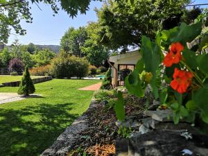 un giardino con un muro in pietra e fiori rossi di Casa do Passal Country House a Paço de Sousa