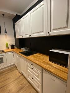 a kitchen with white cabinets and a microwave at Apartament Platinum Park in Stargard