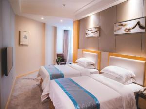 um quarto de hotel com duas camas e uma televisão em Vienna International Hotel Foshan The World of Flowers em Shunde