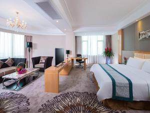 um quarto de hotel com uma cama grande e uma sala de estar em Vienna International Hotel Foshan The World of Flowers em Shunde