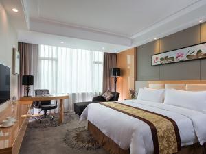 um quarto de hotel com uma cama grande e uma secretária em Vienna International Hotel Foshan The World of Flowers em Shunde