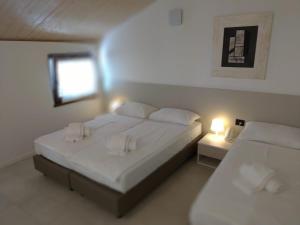 a bedroom with two beds with white sheets and a window at La Corte Room & Relax in Rovereto