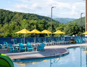 una piscina con sillas azules, mesas y sombrillas en The Lodge at Camp Margaritaville, en Pigeon Forge