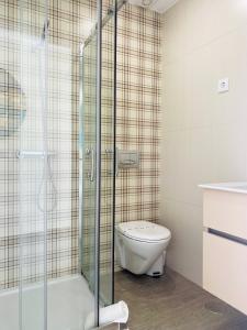 a bathroom with a toilet and a glass shower at Batata - Estúdios in Nazaré