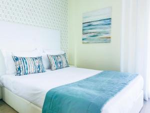 a bedroom with a white bed with pillows on it at Batata - Estúdios in Nazaré