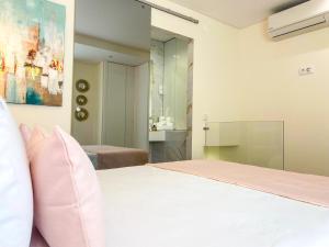 a bedroom with a white bed and a bathroom at Batata - Estúdios in Nazaré